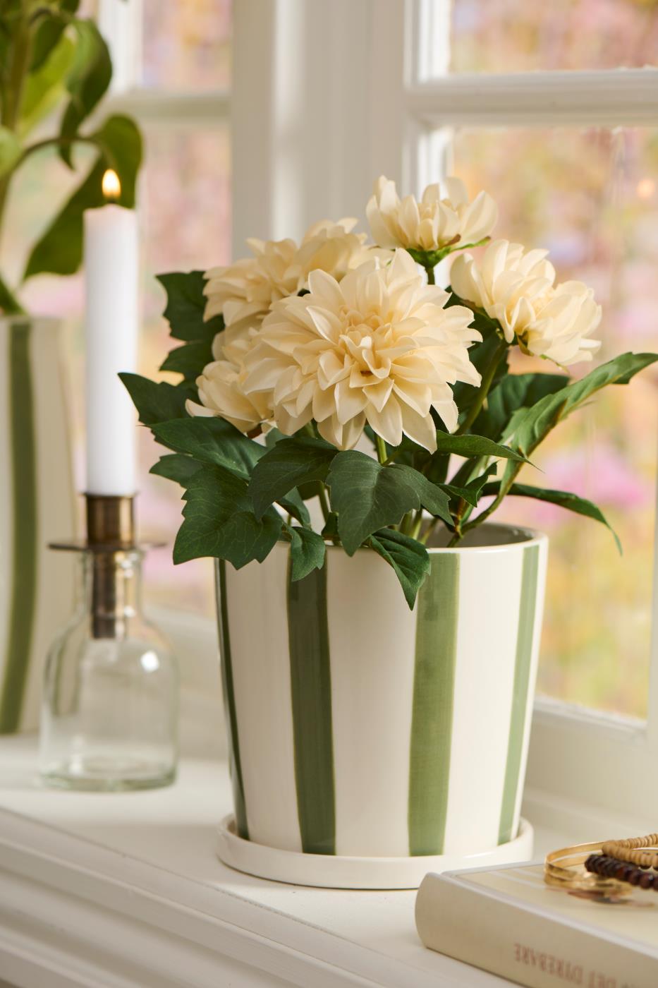 Kunstig lysegul Dahlia i stribet urtepotte i vindueskarm