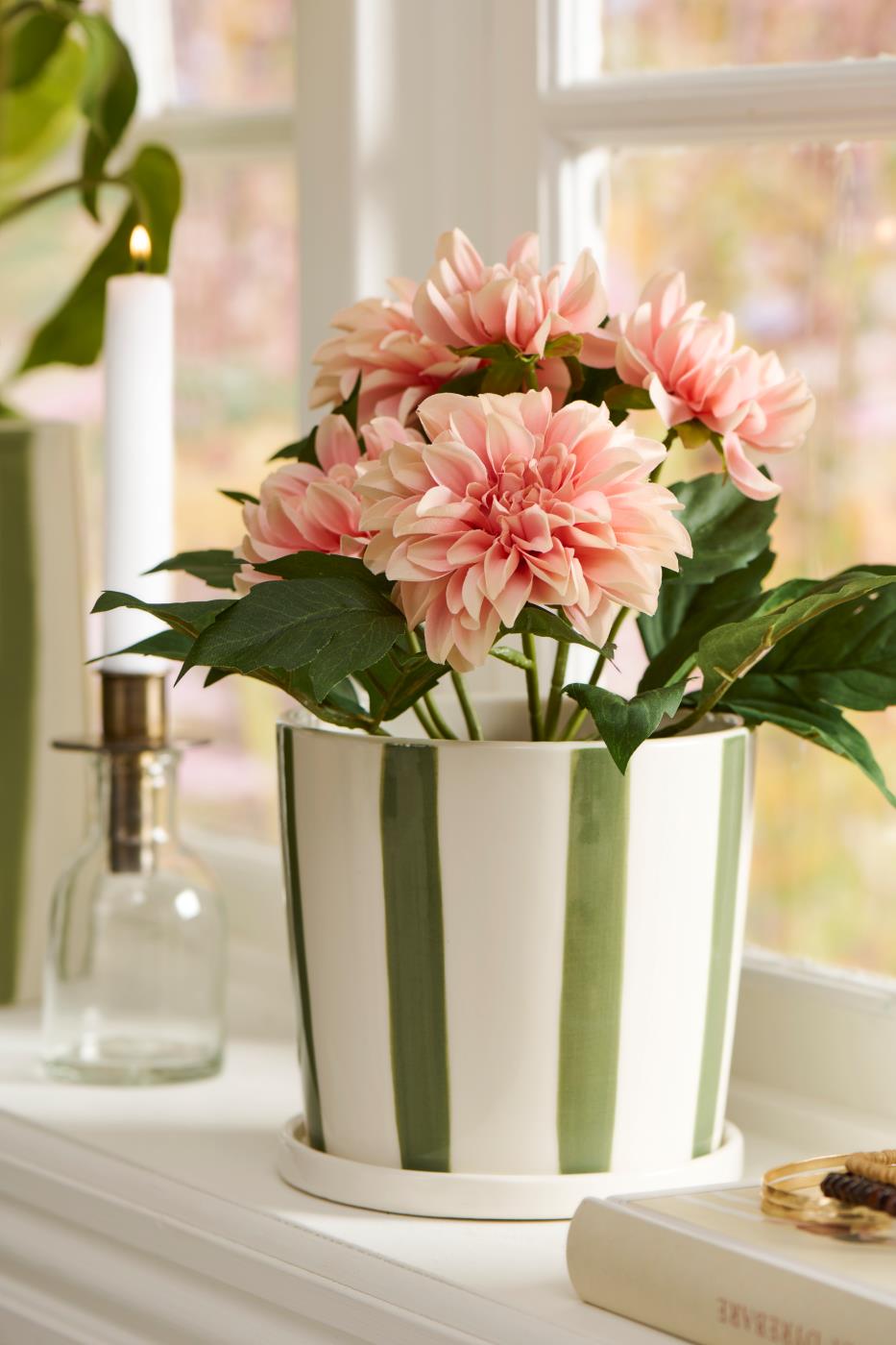 Kunstig rosa Dahlia i stribet urtepotte i vindueskarm