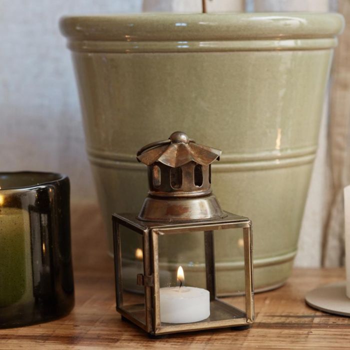Ib Laursen mini lanterne med bølget skorsten med lys i foran en grøn urtepotte
