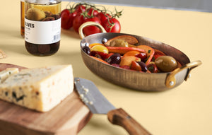 Smørebræt i akacietræ med ost på stående på bord med tapas