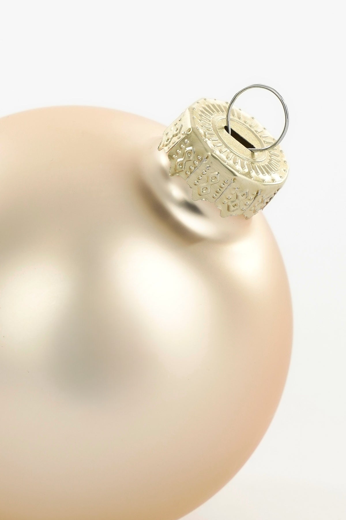 Toppen av en matt cremefärgad julgranskula i glas