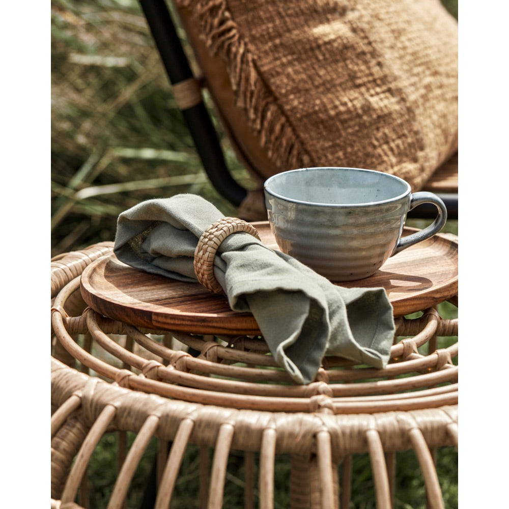 Naturfarvet servietring fra House Doctor rundt om en stofserviet liggende på et bord