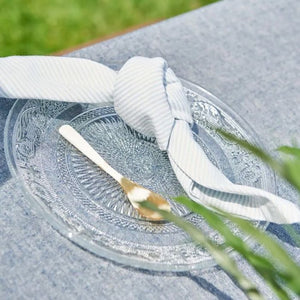 Speedtsberg stofserviet med lyseblå striber bundet i knude på en glastallerken