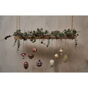 Julekugler fra Speedtsberg hængende under julepyntet hylde.