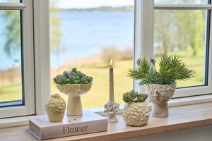 Vase i lysegul keramik med blomstermønster pynter i en vindueskarm