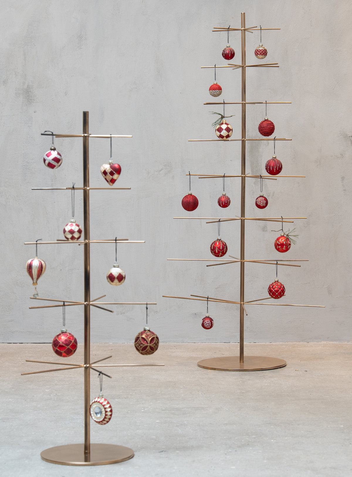 Julgranar i metall prydda med glasornament i röda nyanser från Speedtsberg