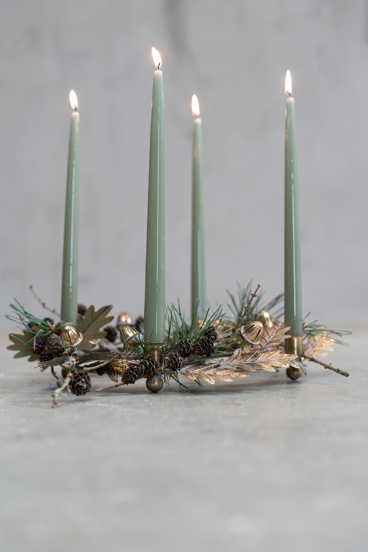 Adventsljusstake med ekollon och blad i antik guldfärg från Speedtsberg, pyntad med silkesgran och dovgröna adventsljus