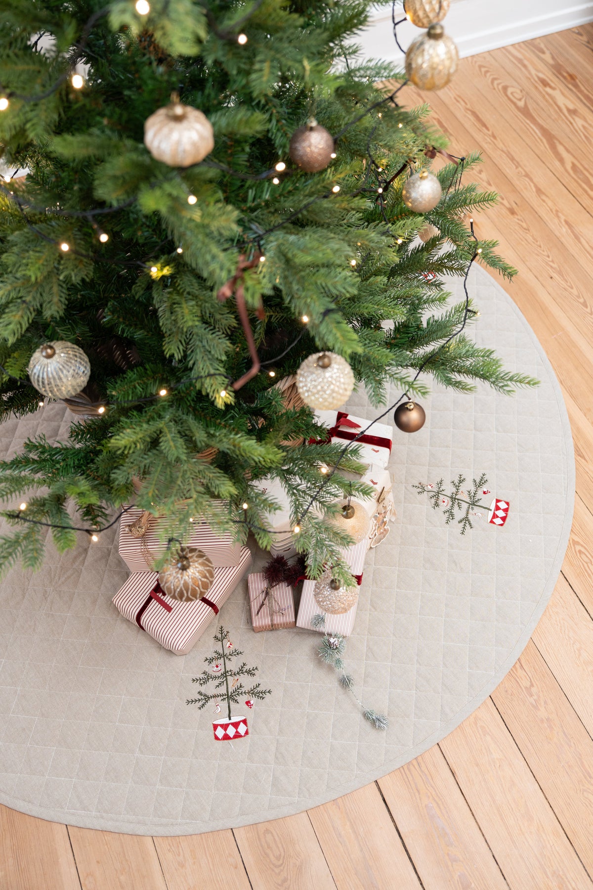 Pyntad julgran stående på en quiltad julgranskjol med broderi från Speedtsberg