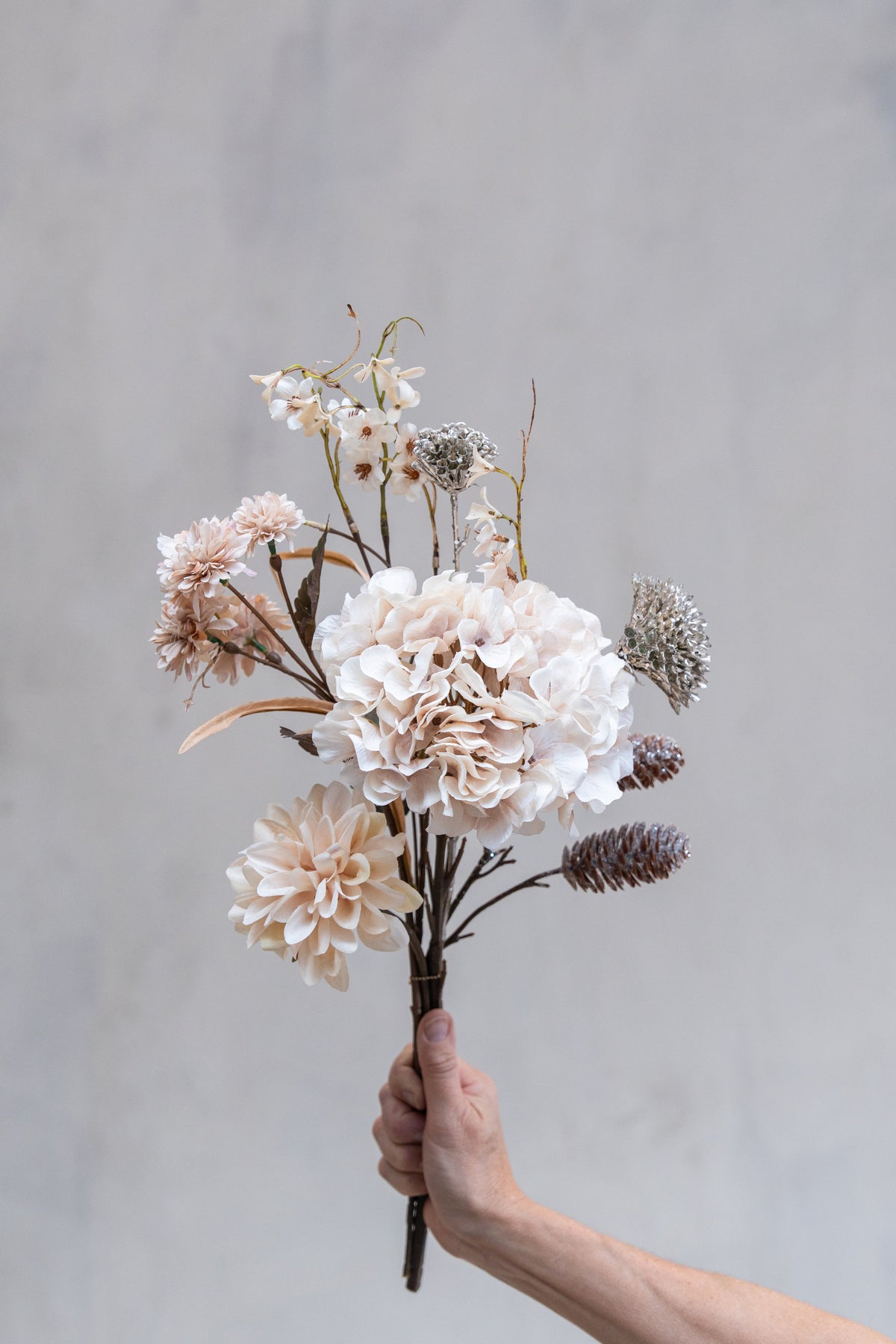 Bukett med konstgjorda rosa blommor och grenar med kottar och glitter från Speedtsberg