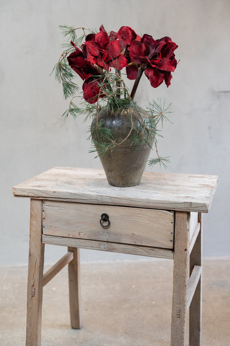 Bukett med konstgjorda stjälkar av amaryllis med vinröda blommor och tallkvistar i vas