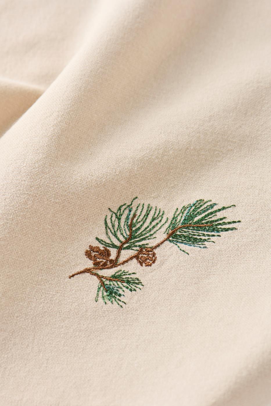 Motivet på tygservetten Tradition: tallkvist med kottar från Ib Laursen i närbild