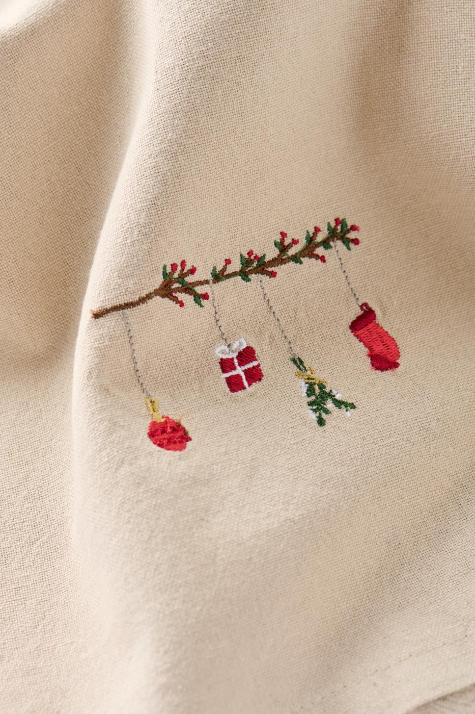 Närbild av linfärgad tygservett med motiv: hängande julpynt i form av en kvist (Tradition) från Ib Laursen