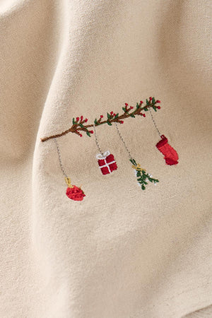 Närbild av linfärgad tygservett med motiv: hängande julpynt i form av en kvist (Tradition) från Ib Laursen