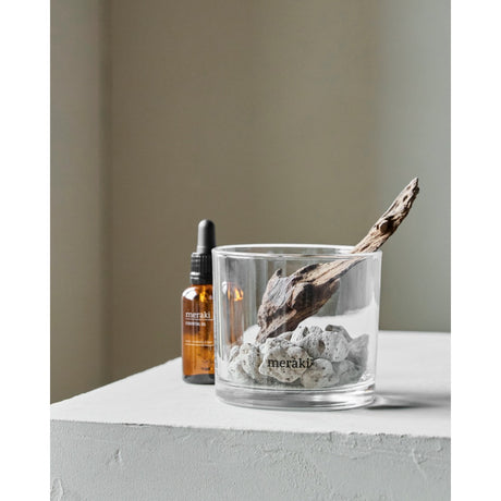 Diffuser med lavasten og træ stående på bord med duftdråberne i en flaske