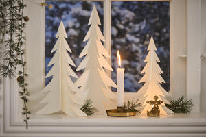 Hvide juletræer i papirklip fra Ib Laursen stående i vindueskarm