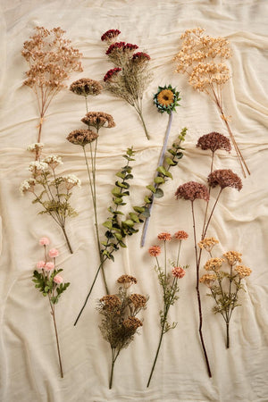 Kunstige blomsterstilke og bladgrene fra Ib Laursen på et hvidt lagen