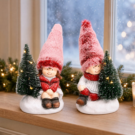 Vinterbarn i snön med julgranar med ljus