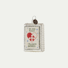 Julmärkesornament 2026 med flätat julhjärta, händer som håller varandra och silverfärgad glitterkant