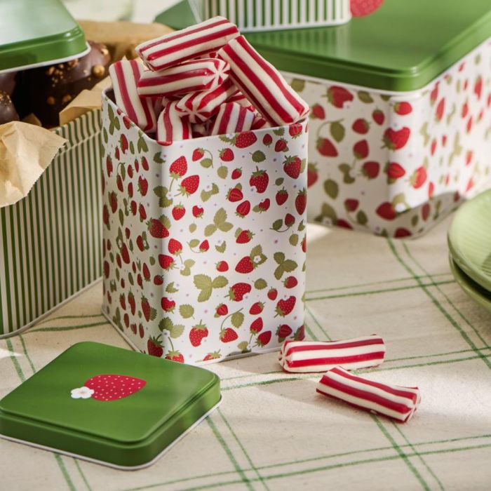 Ib Laursen høj kagedåse med jordbærmotiv og grønt låg fyldt med rød/hvide aflange bolsjer.