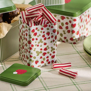 Ib Laursen høj kagedåse med jordbærmotiv og grønt låg fyldt med rød/hvide aflange bolsjer.