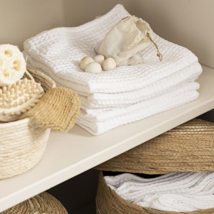 Stak af hvide Liseleje håndklæder 50x100 cm fra Ib Laursen på en hylde