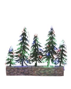 Snötäckta träd på en stenmur med flerfärgade lampor